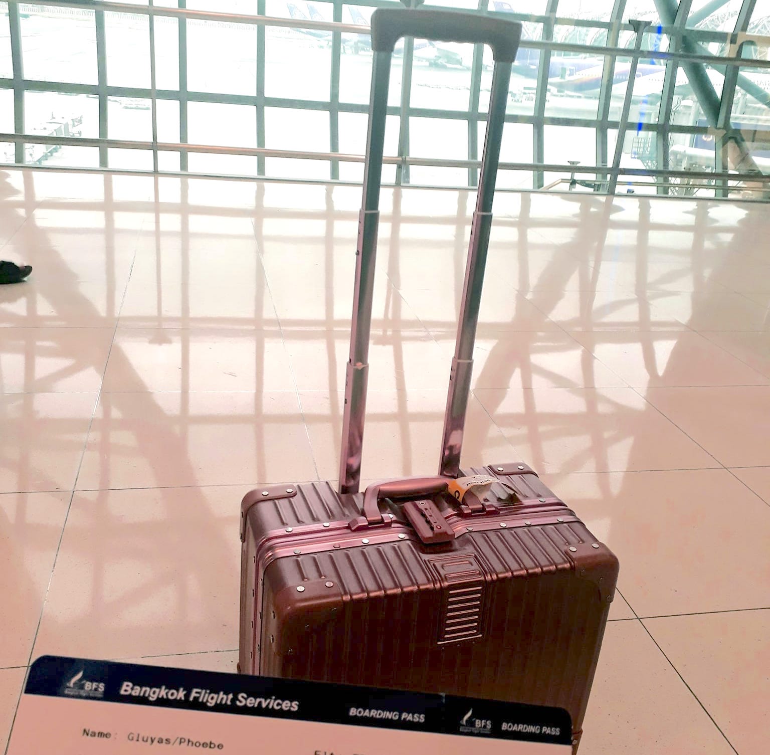 suitcase in an airport with boarding pass